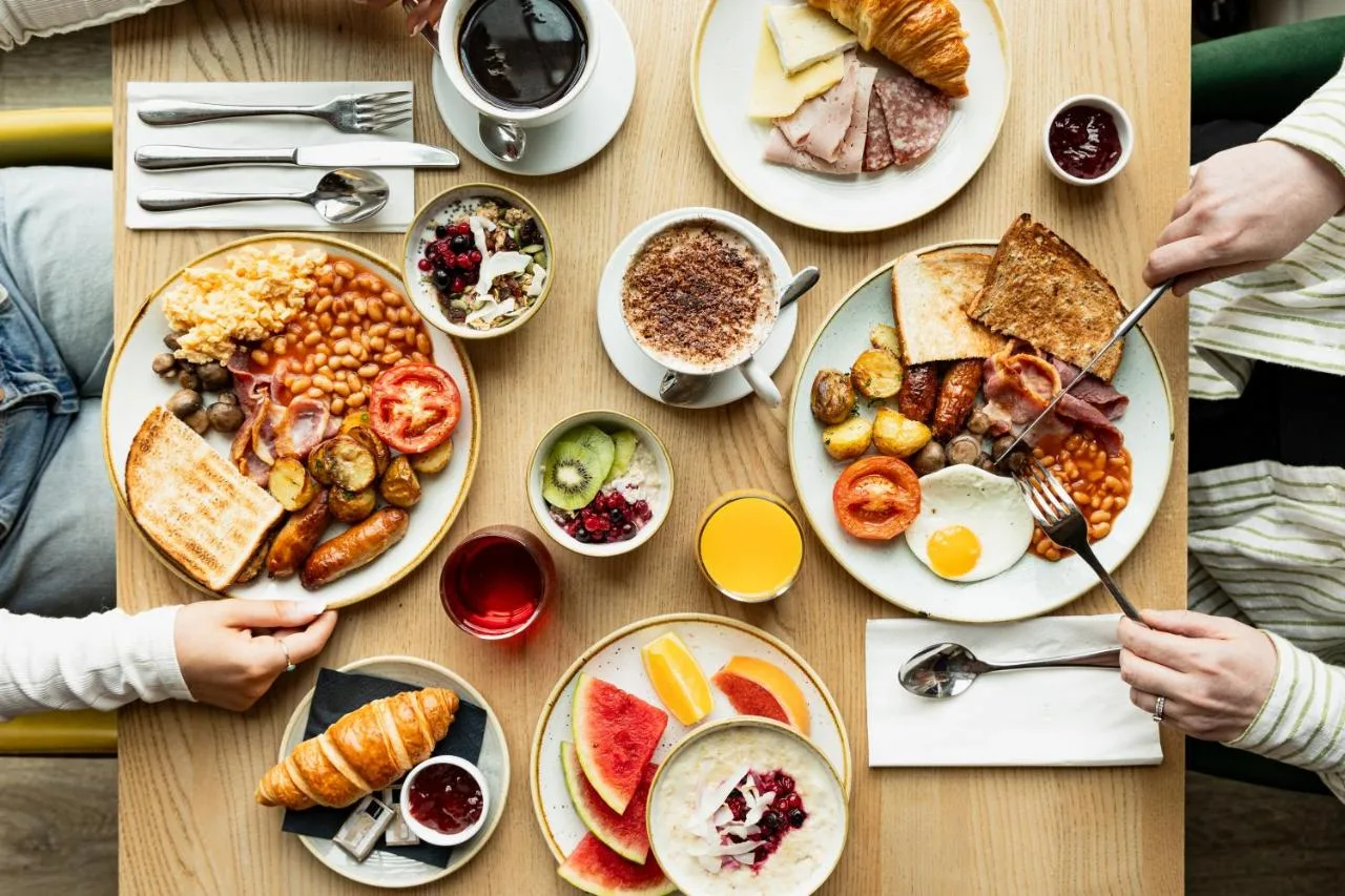 a table with plates of breakfast food on it at Leonardo Edinburgh City in Edinburgh